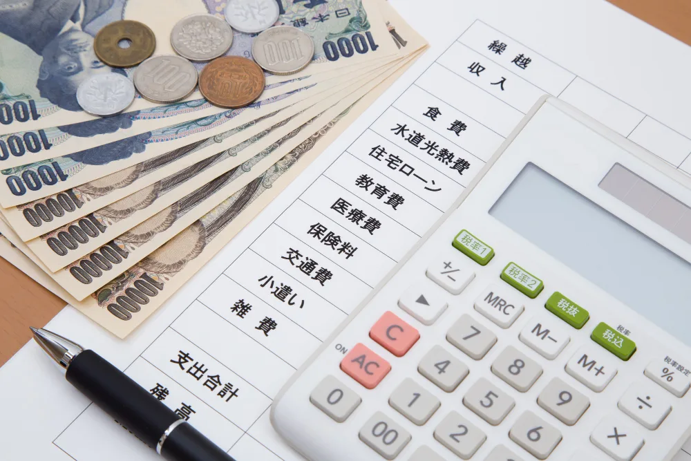 お札と硬貨、家計簿と電卓の写真